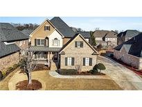 Brick two-story house with a gray roof, landscaping, and a long driveway at 1054 Sw Morgan Garner Dr, Lilburn, GA 30047