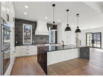 A spacious white kitchen with modern appliances, dark stone countertops, and three pendant lights above the island at 120 Thome Dr, Alpharetta, GA 30022