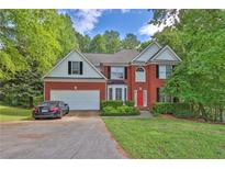 Beautiful two-story brick home with a well-manicured lawn and a bright red front door at 625 Piping Rock Pt, Lawrenceville, GA 30043