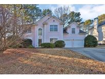 Two-story pink stucco house with a two-car garage and landscaping at 1035 Bridle Path Dr, Lawrenceville, GA 30045