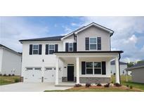Charming two-story home with a two-car garage, covered porch, and landscaped front yard offers an inviting curb appeal at 146 Oakchase Park Ln, Hampton, GA 30228