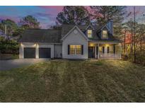 Charming home with a two-car garage, inviting front porch, and well-manicured lawn at twilight at 11489 Highway 36, Covington, GA 30014