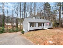 Charming single-Gathering home with gray siding, black shutters, and an American flag, nestled among trees at 1203 Willow Nw Ct, Kennesaw, GA 30152