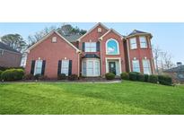 Brick two-story house with a large front yard and landscaping at 4740 Eagles Ridge Loop, Stonecrest, GA 30038