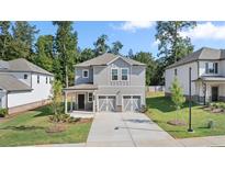 Two-story home with gray siding, two-car garage, and landscaped lawn at 1908 Holmsey Se Cir, Conyers, GA 30094