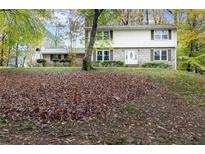 Charming two-story home with brick accents, landscaped front yard, and mature trees during the autumn season at 620 Oakstone Way, Roswell, GA 30075