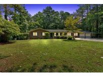 Charming brick home with a spacious front yard and mature trees offering shade and curb appeal at 2144 Kennesaw Due West Nw Rd, Kennesaw, GA 30152