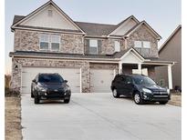 Two-story brick house with a three-car garage and large driveway at 3004 Amabile Rd, Dacula, GA 30019