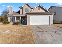 Tan two-story home with a two-car garage and a chimney, with a yard in need of maintenance at 5728 Rock Shoals Way, Atlanta, GA 30349