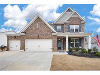 Two-story brick home with a three-car garage and landscaped yard at 7350 Rambling Vale, Cumming, GA 30028