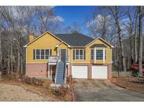 Two-story yellow house with gray stairs, two-car garage, and wooded lot at 2114 Lindley Nw Ln, Kennesaw, GA 30144