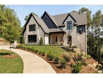 Two-story house with light brick and dark roof, showcasing a charming front porch and landscaping at 6055 Tattnall Overlook, Acworth, GA 30101