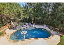 Aerial view of a beautiful backyard pool with lounge chairs and patio furniture surrounded by mature trees at 3950 Stanford Dr, Cumming, GA 30041