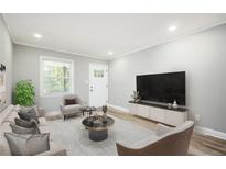 Bright living room with hardwood floors, comfy seating, and large TV at 2198 Star Mist Sw Dr, Atlanta, GA 30311