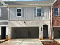 Two-story townhome featuring a brick and gray facade, with a spacious drive-in garage and an arched entryway at 405 Carrera Ln, Acworth, GA 30102