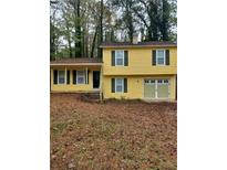 Cute yellow house with green shutters, a two-car garage, and a yard at 701 Boone Ct, Stone Mountain, GA 30088