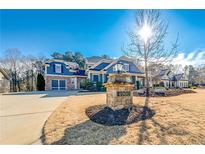 Charming two-story blue home featuring an attached two-car garage, a manicured lawn, and tasteful landscaping at 4960 Shade Creek Xing, Cumming, GA 30028