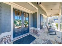 Charming front entrance featuring double doors with glass panels and decorative wreaths, stone porch, and rocking chairs at 4960 Shade Creek Xing, Cumming, GA 30028