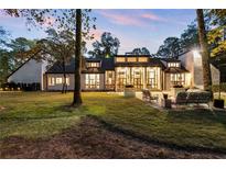 Stunning exterior of the home with a large yard and patio, filled with outdoor seating and large picture windows at 9650 Coleman Rd, Roswell, GA 30075