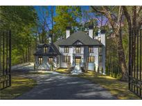 Stately two-story home with a circular driveway surrounded by mature trees and professional landscaping at 5390 Harrowood Ln, Sandy Springs, GA 30327