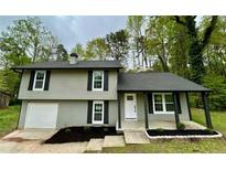 Inviting split-level home featuring a gray exterior, black shutters, and a well-manicured front yard with mulch at 5507 Flat Shoals Pkwy, Decatur, GA 30034