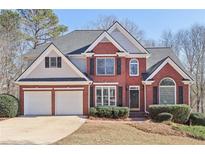 Brick two-story house with a two-car garage and landscaped lawn at 5034 Hickory Hills Dr, Woodstock, GA 30188