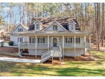 Two story house with wraparound porch, gray siding, and landscaping at 3820 Mink Livsey Rd, Snellville, GA 30039
