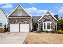 Charming stone-accented home featuring a two-car garage and inviting front porch, perfect for suburban living at 173 Mill Creek Dr, Canton, GA 30115