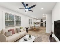 Bright living room featuring a ceiling fan, many windows, and an open floor plan to the dining area and modern kitchen at 1288 Almont Sw Dr, Atlanta, GA 30310