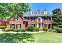 Stately brick home with black shutters, dormer windows, and lush front yard landscaping on a sunny day at 340 Kincardine Way, Alpharetta, GA 30022