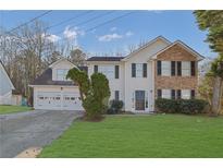 Charming two-story home with a manicured lawn, a two-car garage, and a stone and vinyl facade at 2295 Creekview Trl, Decatur, GA 30035