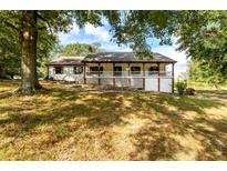 Ranch house with a large front porch, surrounded by lush landscaping at 3241 Briscoe Rd, Loganville, GA 30052