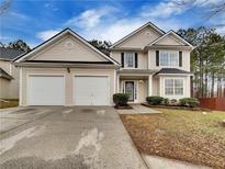 Two-story house with beige siding, two-car garage, and landscaped lawn at 129 Baywood Xing, Hiram, GA 30141