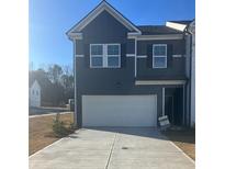 Two-story townhome with gray siding, white garage door, and landscaping at 1200 Westhampton Way # 141, Villa Rica, GA 30180