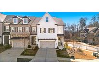 Three-story townhome with white exterior, two-car garage, and landscaping at 1 Ganel Ln, Alpharetta, GA 30009