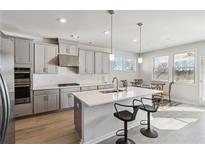 This kitchen features stainless steel appliances, gray cabinets, an island with a sink, and hardwood floors at 2131 Landsburg Way, Lawrenceville, GA 30043