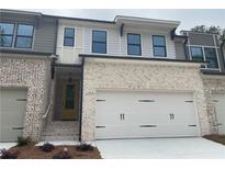 New construction townhome features a two-car garage, light brick, black gutters, and a yellow front door at 1366 Lucan Ln # Wc225, Lawrenceville, GA 30043