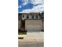 Two-story townhome with light brick exterior, two-car garage, and landscaping at 1366 Lucan Ln # Wc225, Lawrenceville, GA 30043