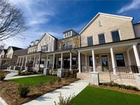Charming townhomes featuring brick and stone exteriors, covered front porches with columns, and manicured lawns at 130 Chiswick Cir, Alpharetta, GA 30009