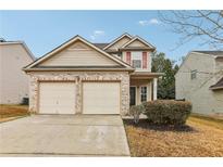 Two-story house with beige siding, brick accents, and a two-car garage at 6057 Hemperly Rd, Atlanta, GA 30349