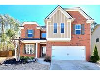 Brick two-story house with a large white garage door and landscaping at 3255 Carrick Rd, Cumming, GA 30040