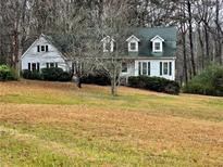 White house with green roof, nestled on a large lot with mature trees at 105 Pine Valley Rd, Hiram, GA 30141