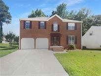 Charming two-story brick home featuring an attached two-car garage, well-manicured lawn, and classic architectural details at 1043 Carriage Trace Cir, Stone Mountain, GA 30087