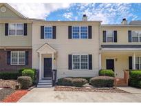 Two-story townhome with light beige siding, black shutters, and a small front yard at 74 Venture Path, Hiram, GA 30141