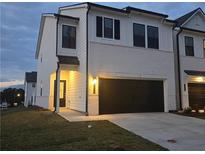Two-story home with white brick exterior, black garage door, and well-manicured lawn at 1935 Westwind Street (Lot 157), Lawrenceville, GA 30043