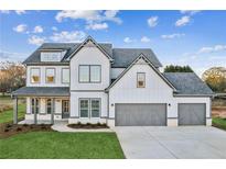 Two-story farmhouse with gray accents, three-car garage, and landscaped yard at 2799 Porches Ln, Dacula, GA 30019