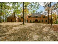 Brick home with a large front yard, set back from the road among tall trees at 115 Russell Rd, Roswell, GA 30075