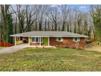 Brick ranch house with green shutters, covered porch, and landscaped lawn at 5310 Timbo Ln, Mableton, GA 30126