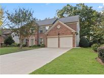 Charming two-story brick home featuring an attached two-car garage and a well-manicured front lawn at 1805 Aurelia Dr, Cumming, GA 30041