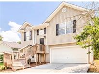 Two-story house with beige siding, a wooden deck, and a two-car garage at 9129 Jefferson Village Sw Dr, Covington, GA 30014